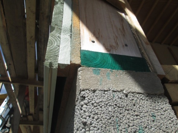 Tässä vielä seinän rakennetta alaviistosta: Kellarin kevytsoraharkon päällä on tasoitevalu. Sen päällä on 6mm paksu ja  200mm leveä solumuovikaista (ei näy), ja sen päällä kyllästetty alaohjauspuu 50x175mm (näkyy vihreänä). Solumuovin tarkoitus on estää kylmästä johtuva kondenssikosteus alimmaiseen puuhun, joka on vielä kyllästetty siltä varalta, että se kuitenkin saa kosteutta joskus. Ulkovuorilauta on vaalean sävyinen, jotta se olisi kesäisin viileä. Ulkovuorilauta on 28mm paksu ja maalattu päistä, myös jokaisen laudan jatkoskohdassa. Ulkovuoren takana on 25mm ilmarako, jota kohden lautoja ei ole maalattu (toki maalinkin pitää hengittää, mutta ilmaraon suuntaan ulkovuorilauta hengittää erityisen hyvin. Toisella puolen ilmarakoa runkoleijona, paksut villa 175mm, sitten höyrynsulkuovi, ohuet villat 50mm ja sisäseinässä 13mm kipsilevy. Nykyisin tällaista taloa ei saisi enää rakentaa, koska määräykset vaatisivat paljon paksummat villakerrokset, mutta meidän talon rakennuslupa ehdittiin hakea ennen 1.7.2012 voimaan tulleita uusia määräyksiä. Seinän U-arvo tässä kuvassa on 0,17. Ikkunoiden U-arvo meillä on 0,80, jolloin 1 neliö ikkunaa vastaa 4,7m2 seinää, jos mietitään lämmönhukkaa rakenteen läpi.