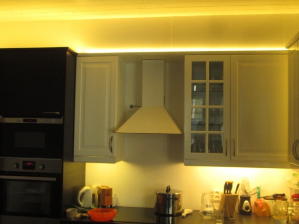 Jos ei kiinnitä huomiota muuttopäivän jälkeiseen sekasotkuun keittiön pöydällä, niin tässä kuvassa näkyy tai pitäisi näkyä muutama juttu valaistukseen liittyen. Ylävasemmassa kulmassa LED-nauhan valo näyttää hyvältä ja tasaiselta, siellä LED-nauha on yläsokkelista etäämmällä noin 30cm, kun tumma kaapisto on paksumpaa kuin valkoinen. Valkoisen kaapiston kohdalla LED-nauha kurvaa aivan kiinni yläsokkeliin - josta loistaa pistemäinen valokuvio, joka ei ole enää niin hieno kuin vasen yläkulma, jossa valo heijastuu joka suuntaan tasaisena, eikä näy mistä suunnasta se tulee.  Kaapistojen alalaidassa on loistevaloputket, joista tulee tasainen valo - LED:llä toteutettuna tässä näkyisi pistemäisiä laikkuja mm. niissä kaapiston pinnoissa jotka valojen päissä menevät seinää kohden ja joutuvat kulmakohdassa "liian lähelle" LED-nauhaa. Loistputkia ei kuitenkaan voi laittaa esim. kaapistojen päälle, koska ne näkyisivät sieltä, ja valojuovasta tulisi katkonainen (jos ei saa putkia limittäin). Eikä loisteputkissa noissa tiloissa ole mitään järkeä muutenkaan.