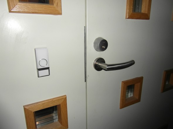 Ovipainikkeen voi asentaa ulko-ovelle siististi joko 2-puolisella teipillä (tuli mukana), tai 2 pienellä ruuvilla (nekin tuli mukana). Tässä käytetty 2-puolista teippiä.